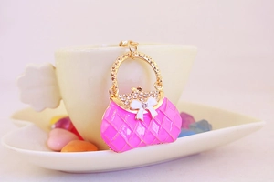 Close-up of pink enamel handbag keychain pendant with sparkling rhinestones and white bow