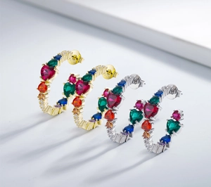 Macro shot of silver C-hoop earrings featuring colorful heart-shaped cubic zirconia stones