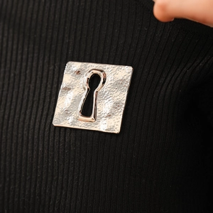 Close-up of vintage square silver brooch with keyhole cutout on black knit fabric