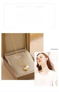 Détail d'un collier en titane doré avec pendentif opale et disque métallique en boîte cadeau