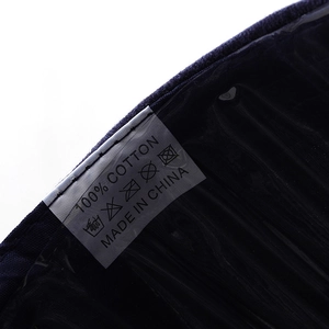 Macro shot of 100% cotton wash label with care symbols on a dark navy baseball cap