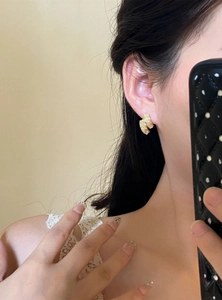 Vue détaillée de boucles d'oreilles dorées avec texture martelée portées par le modèle