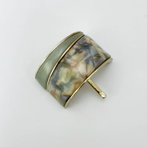 Detail of olive green and marble resin ponytail clip with gold metal frame finish