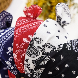 Detail of four paisley pattern knotted headbands in navy, red, white, and black colors