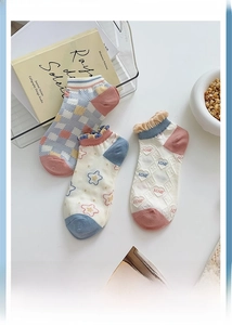 Detail of floral and checkered pattern socks with ruffled cuffs on a cozy white desk