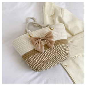 Flat lay of a woven tote bag with a champagne bow decoration on a white linen surface