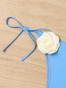 Detail of light blue bikini bottom with a decorative 3D white fabric flower and side ties