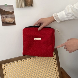 Rode make-up tas van bouclé fleece in een lifestyle setting, zachte reistas