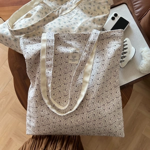 Detail of floral cotton tote bags with shoulder straps on a wooden table setup
