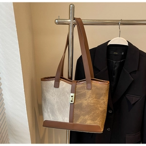 Detail of canvas and leather patchwork tote bag with stylish metal lock closure
