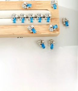 Detail of blue zircon waterdrop conch earrings on a wooden jewelry display stand