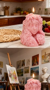 Artistic pink 3D goddess candle with floral hair carvings lit in a warm studio