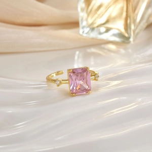 Detail of gold-plated ring featuring a pink rectangular crystal and micro-pave accents