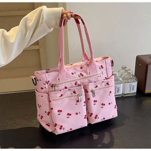 Close-up of pink tote bag with cherry print featuring multiple functional side pockets