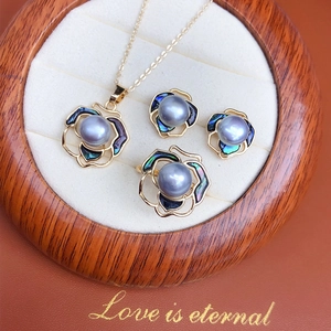 Golden jewelry set featuring grey pearls and abalone shell floral pendants in a wood box