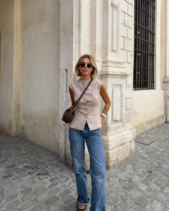Gilet beige in stile britannico con bottoni frontali abbinato a jeans blu a taglio dritto