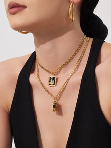Close-up of double layered gold chains with rectangular pendant and pearl detail