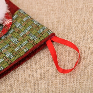Close-up of small burlap Christmas stocking showing red hanging loop and green woven texture