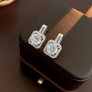 Macro shot of silver vintage square halo earrings with sparkling zircon on a leather box