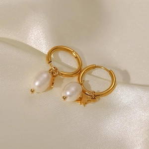 Close-up of 18k gold-plated hoop earrings with freshwater pearls and star charms on silk