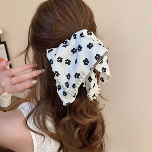 Floral fabric hair scrunchie with white pearl chains shown on a low ponytail
