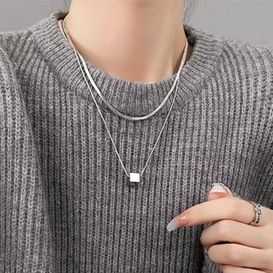 Close-up of double-layer silver square pendant necklace styled on a grey knit sweater