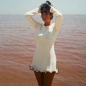 Dettaglio dell'abito corto bianco con orlo a balze nere a contrasto su modella professionale