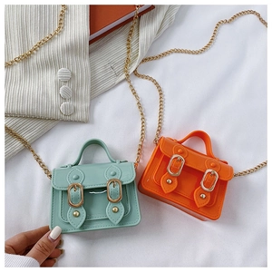 Detail view of mint green and orange mini jelly crossbody bags with gold chain straps