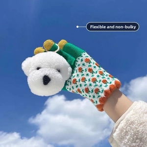 Close-up of green knitted glove with orange flower and white plush puppy dog decor