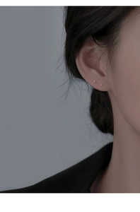 Close-up of minimalist tiny silver sphere stud earring worn on ear for daily styling