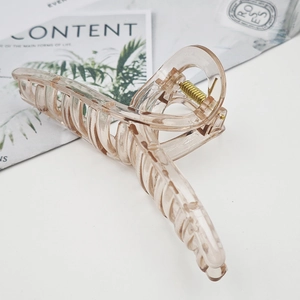 Detail of a champagne translucent large hair claw clip with golden spring mechanism