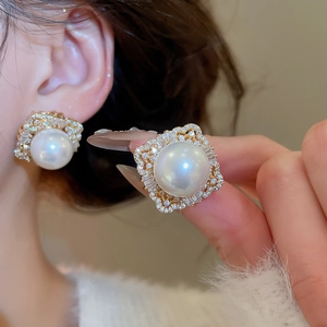 Close-up of geometric square earrings with cream pearls and sparkling zircon accents