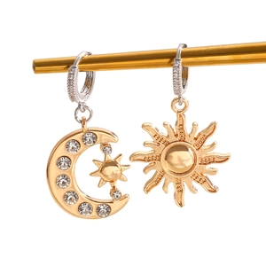Détail de boucles d'oreilles asymétriques soleil et lune avec incrustation de zircon
