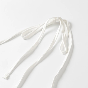 Détail macro d'un nœud en ruban de satin blanc avec surpiqûres de haute qualité