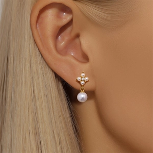 Close-up of a minimalist gold teardrop stud earring with pearl accents on a model