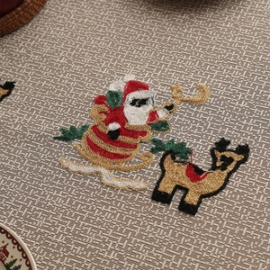 Macro shot of embroidered Santa Claus and reindeer design on red polyester tablecloth