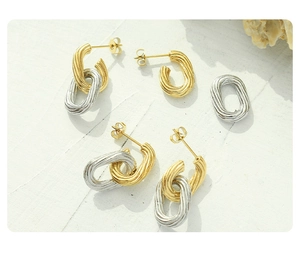 Detailed view of textured gold and silver twist hoop earrings on a shell background
