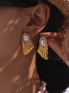 Detailed close-up of vintage gold shell earrings with elegant white pearl inlay