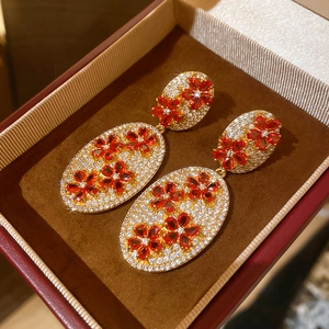 Detailed macro view of vintage gold flower earrings with red zircons and white crystals