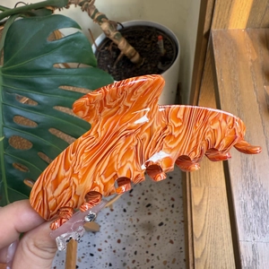 Macro detail of large acetate hair claw clip featuring orange and white marble patterns