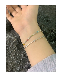 Detailed view of layered S925 silver bracelets with colorful beads on a grey stone background