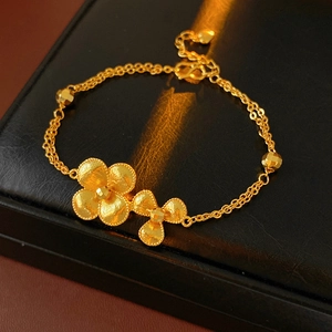 Detailed close-up of gold flower bracelet with matte petals and double-chain structure