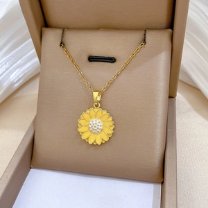 Macro detail of sunflower pendant featuring yellow enamel petals and golden link chain