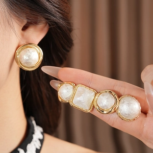 Detail of gold-plated circular earrings with creamy resin pearls on a female model