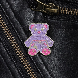 Close-up of a purple enamel bear brooch with graffiti patterns on black leather jacket