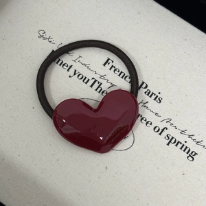 Detail of burgundy heart-shaped acetate hair tie with gold 'France Handmade' lettering