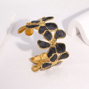 Détail du bracelet ouvert en acier doré avec fleurs en émail noir élégantes