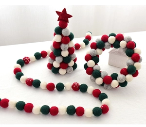 Detailed view of red, green, and white wool felt ball garland and Christmas tree ornaments