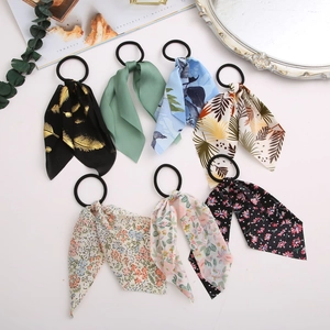 Detailed flat lay of seven various floral and patterned ribbon hair scrunchies with props
