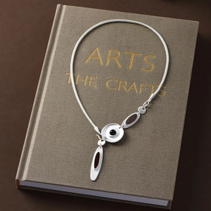 Artistic silver snake chain necklace with irregular drip oil charms on a vintage book cover